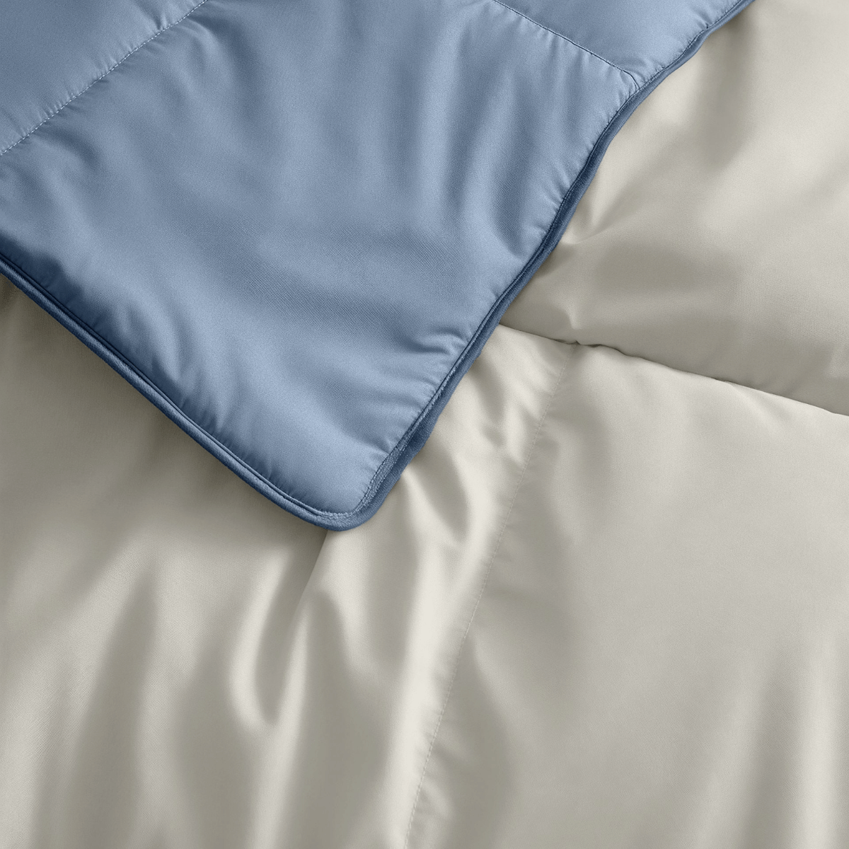 Nahaufnahme einer gesteppten blauen Decke auf einer beigen Bettdecke, beide mit weicher Textur - Zelesta Premiumbed Baumwolle - Dream Blue & Cream, wie geschaffen für ein verwöhnendes Schlaferlebnis.