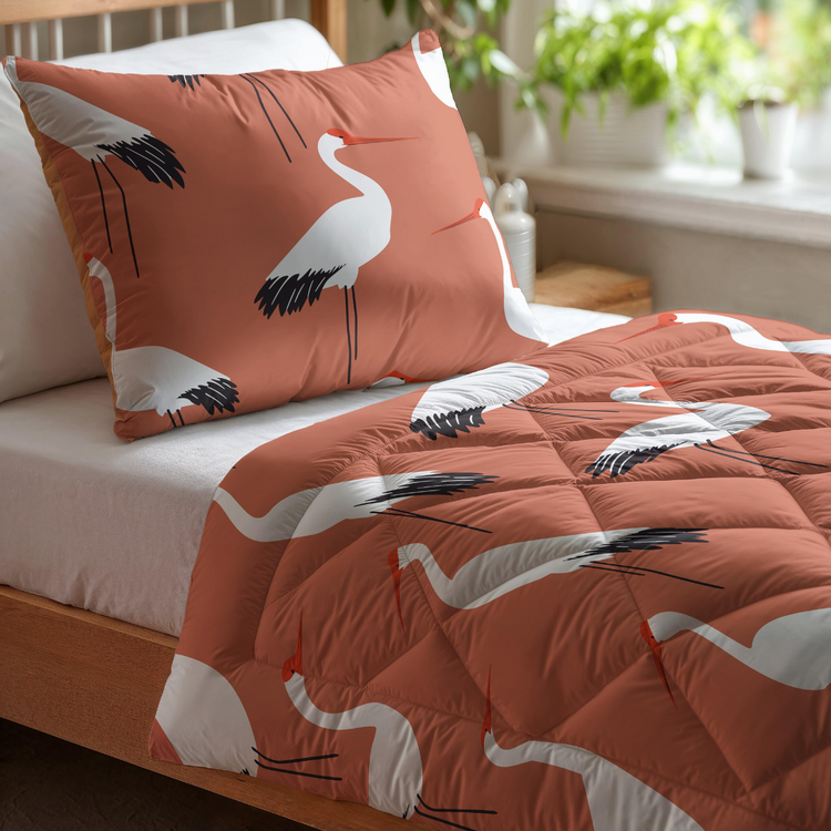 Das Zelesta Kiddybed Baumwolle - Terra Crane, ein rostfarbenes Bettdecken- und Kissenset mit weißen Kranichmustern, ist hypoallergen und sitzt an einem mit Grünpflanzen dekorierten Fenster.