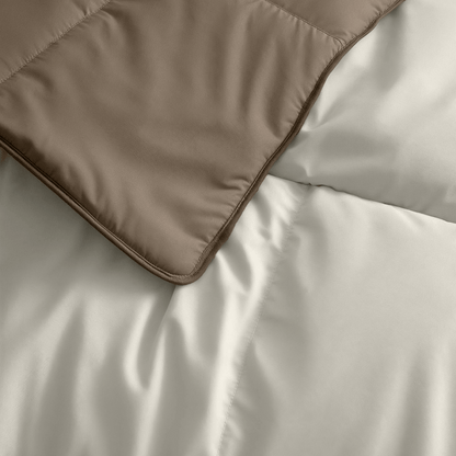 Nahaufnahme des Zelesta Premiumbed Baumwolle - Taupe & Cream, das eine weiße Bettdecke teilweise überlappt. Beide sind mit einem Steppmuster aus unserer luxuriösen Bettdeckenkollektion versehen.