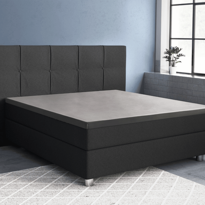 Ein modernes schwarzes Polsterbett mit getuftetem Kopfteil steht in einem Schlafzimmer mit blauen Wänden, das mit dem Primaviera Deluxe Topper Satin Deluxe Spannbettuch in Grau ausgestattet ist, neben einem großen Fenster und einer kleinen Topfpflanze.