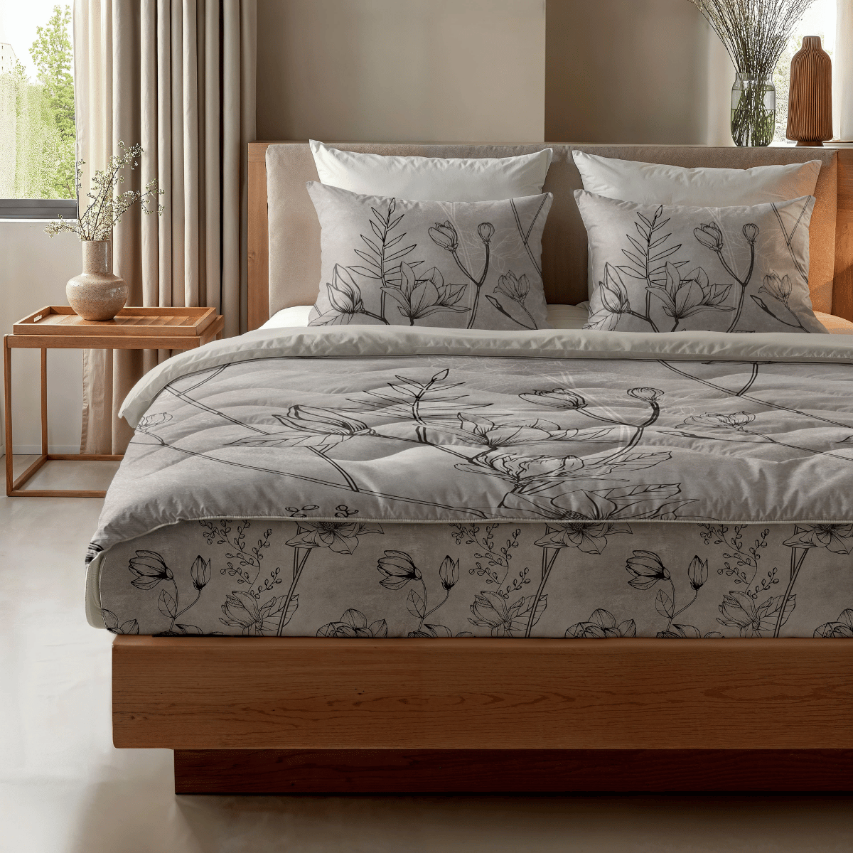In einem hellen Schlafzimmer steht das Zelesta Royalbed - Butterfly Forest, ein Bett mit Holzrahmen und grauer Bettwäsche mit Blumenmuster, zwei Kissen, eine antiallergische Bettdecke und ein Beistelltisch mit einer Vase und neutralem Dekor.