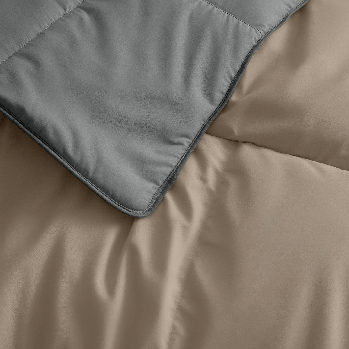 Nahaufnahme eines Bettes mit dem Zelesta Premiumbett Baumwolle - Anthrazit & Taupe, mit einer anthrazitfarbenen und einer taupefarbenen Bettdecke, die beide mit Öko-Daunenfüllung hergestellt wurden.
