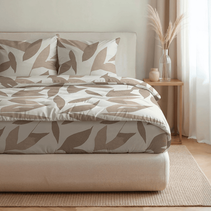 Ein ordentlich gemachtes Bett mit Royalbed Baumwolle - Beige Herbstblatt gemusterte Bettwäsche, zwei Kissen, allergikergeeignete Bettdecke, ein hölzerner Nachttisch mit Dekor, und ein durchsichtiger Vorhang, der natürliches Licht hereinlässt.