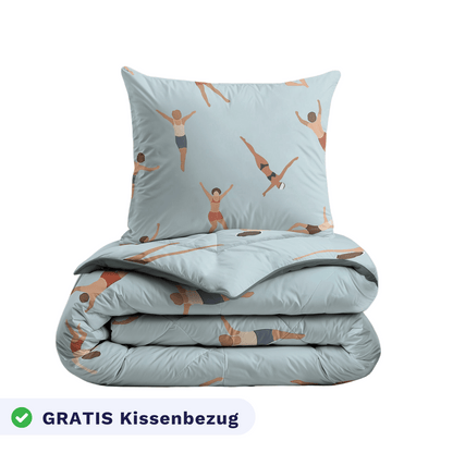 Ein gefaltetes Zelesta Kiddybed Baumwolle - Swimmers Bettdecke und passendes Kissen mit einem hellblauen Bezug mit Schwimmern, hypoallergen, und enthält einen Kissenbezug mit der Aufschrift "GRATIS Kissenbezug" in Deutsch.