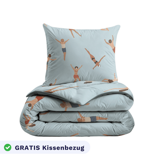 Ein gefaltetes Zelesta Kiddybed Baumwolle - Swimmers Bettdecke und passendes Kissen mit einem hellblauen Bezug mit Schwimmern, hypoallergen, und enthält einen Kissenbezug mit der Aufschrift "GRATIS Kissenbezug" in Deutsch.