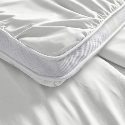 Nahaufnahme des Zelesta Toppers in Weiß mit angepasster Schürze auf einem Bett, mit glattem Stoff, Netzseiten und fortschrittlicher Blue Cell Technology für erhöhten Komfort.