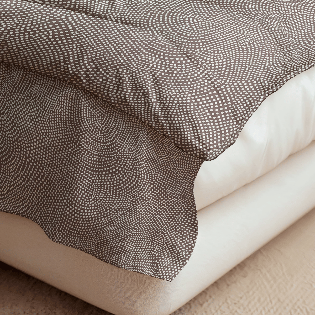 Nahaufnahme einer Bettecke mit der Royalbed Baumwolle - Brown Animal Bettdecke mit braunem und weißem Tiermuster, drapiert über einer cremefarbenen Matratze auf einem strukturierten beigen Boden.