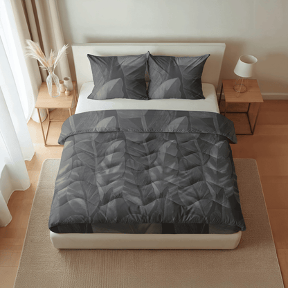 Ein ordentlich gemachtes Bett mit der Royalbed Baumwolle - Black Swan grauen, blattgemusterten, allergikerfreundlichen Bettdecke und passenden Kissen, flankiert von zwei hölzernen Nachttischen in einem minimalistischen, gut beleuchteten Schlafzimmer.