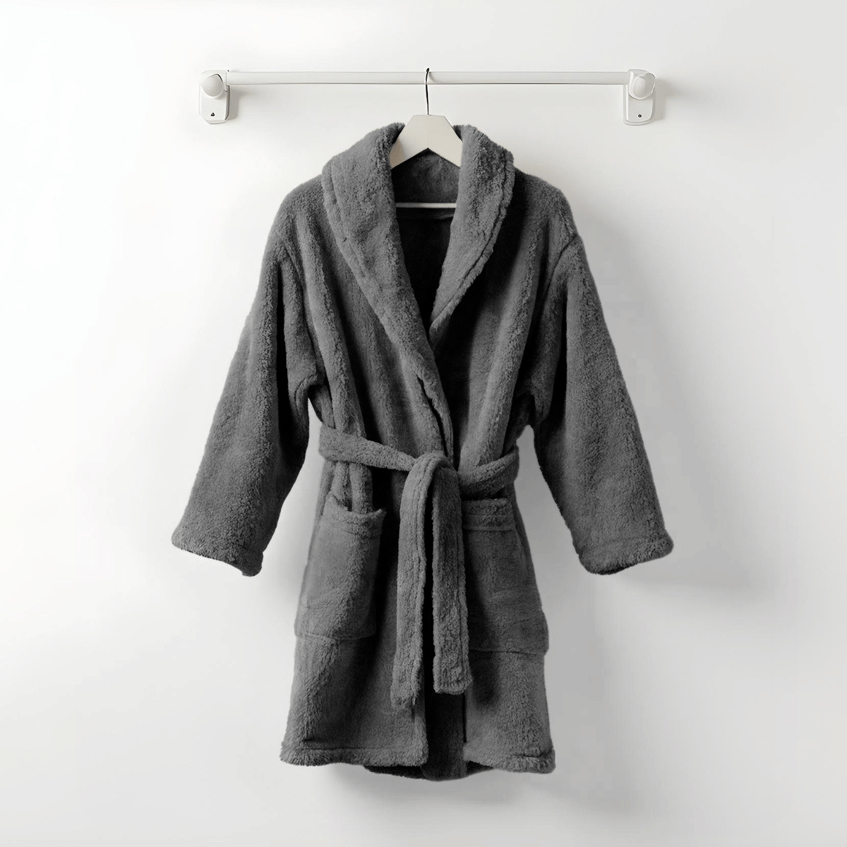 Der Teddy Morgenmantel Anthrazit mit langen Ärmeln, Fronttaschen und Taillengürtel sorgt in kuscheligem Design für wohlige Wärme und hängt stilvoll auf einem Wandhaken.