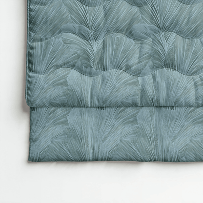 Das Royalbed Baumwolle ist eine gefaltete Bettdecke in botanischem Grün, die auf einer weißen Oberfläche gezeigt wird und eine temperaturregulierende Bettdecke bietet, die perfekt für Allergiker ist.