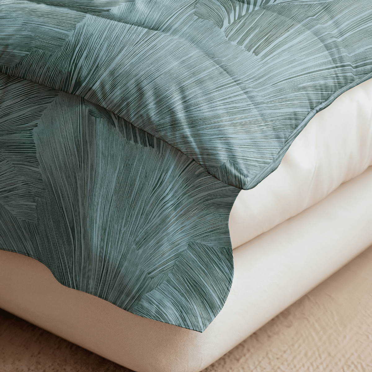 Nahaufnahme einer Bettecke mit einer blattgemusterten Bettdecke von Royalbed Baumwolle - Botanical Green, die über eine weiße Decke auf einem beigen Teppichboden drapiert ist.