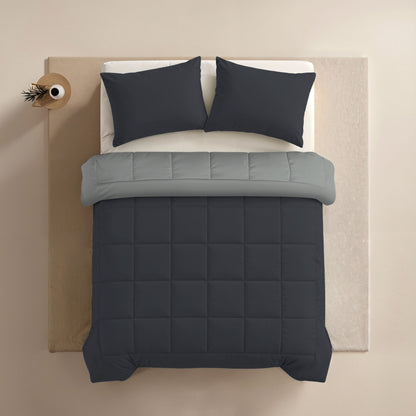 Ein ordentlich gemachtes Bett mit Zelesta Comfort Duo Kissenbezügen Set von 2 - Sanftes Schwarz (80x80cm), einem hellgrauen Oberlaken und einer dunkelgrauen Bettdecke, von oben gesehen auf einem hellen Hintergrund.