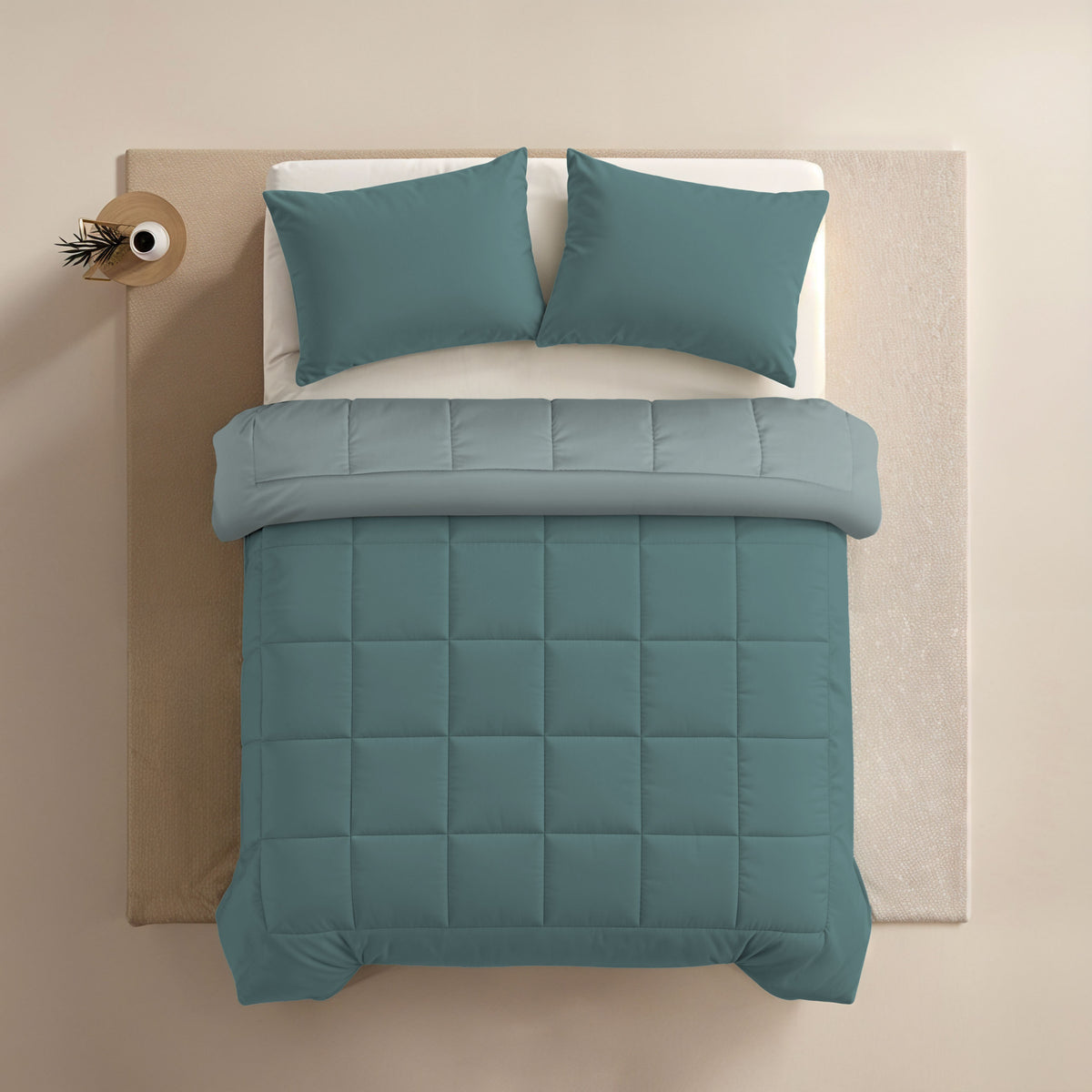Ein ordentlich gemachtes Bett mit tealfarbenen Kissen und einer Zelesta Comfort Duo Bettdecke - Mineral & Hellblau auf einer hellen Matratze, von oben gesehen.