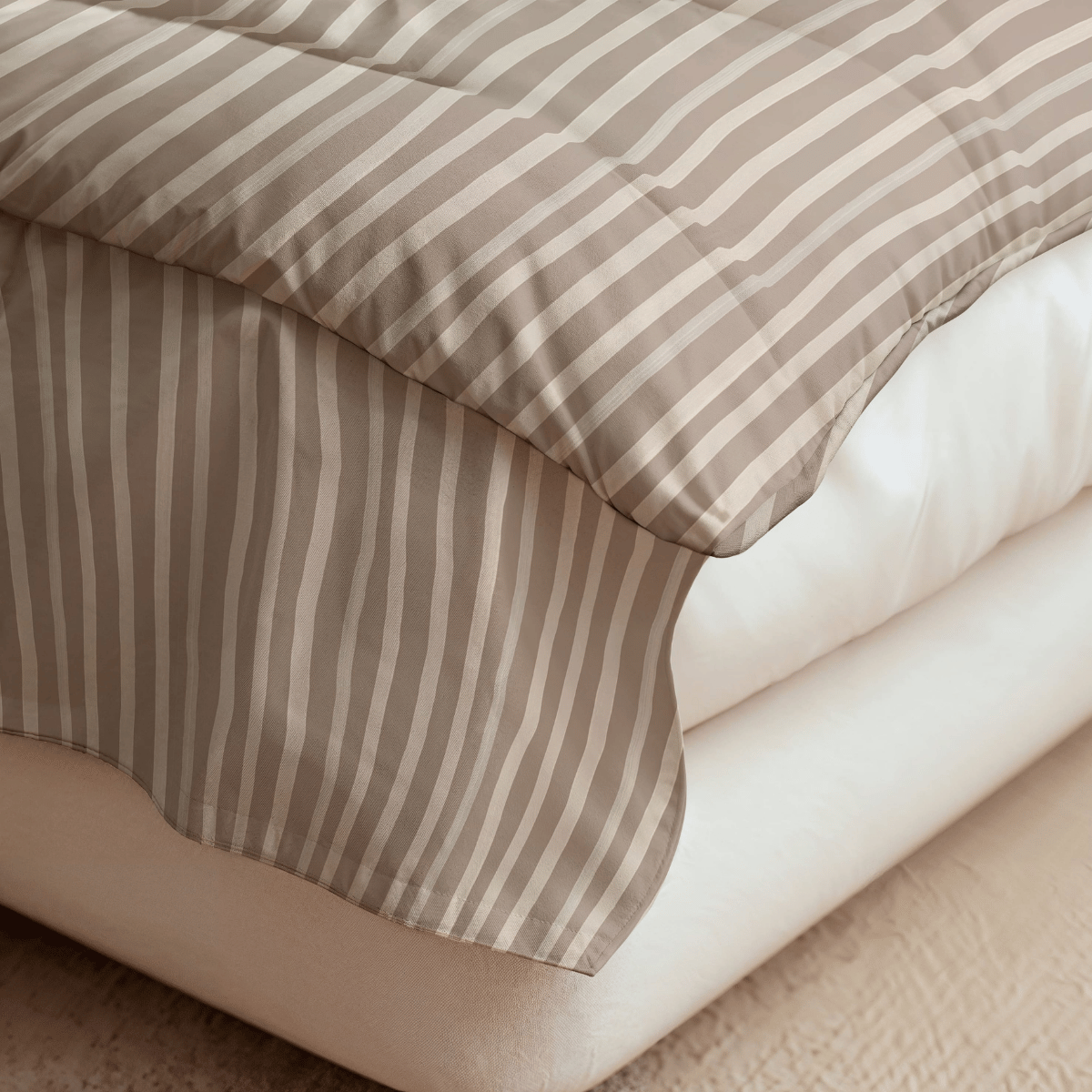 Nahaufnahme eines ordentlich gemachten Bettes mit einer Royalbed Baumwolle - Brown Stripes, allergikergeeigneten Bettdecke, die über den Rand drapiert ist und auf einer weißen Matratze ruht.