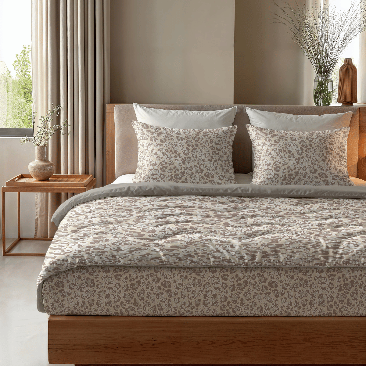 Das Zelesta Royalbed - Sand Panther steht mit Kissen auf einem ordentlich gemachten Bett, daneben ein hölzerner Nachttisch mit einer Vase und einer kleinen Schale in einem sanft beleuchteten Schlafzimmer.