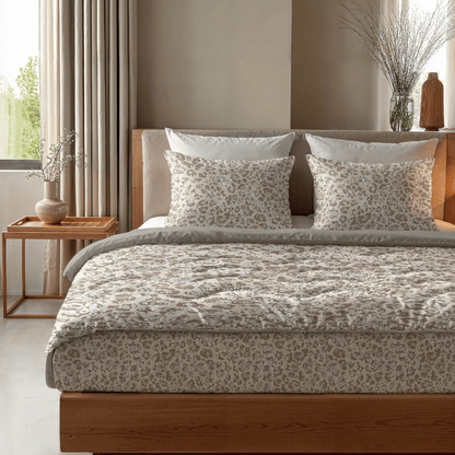 Das Zelesta Royalbed - Sand Panther steht mit Kissen auf einem ordentlich gemachten Bett, daneben ein hölzerner Nachttisch mit einer Vase und einer kleinen Schale in einem sanft beleuchteten Schlafzimmer.