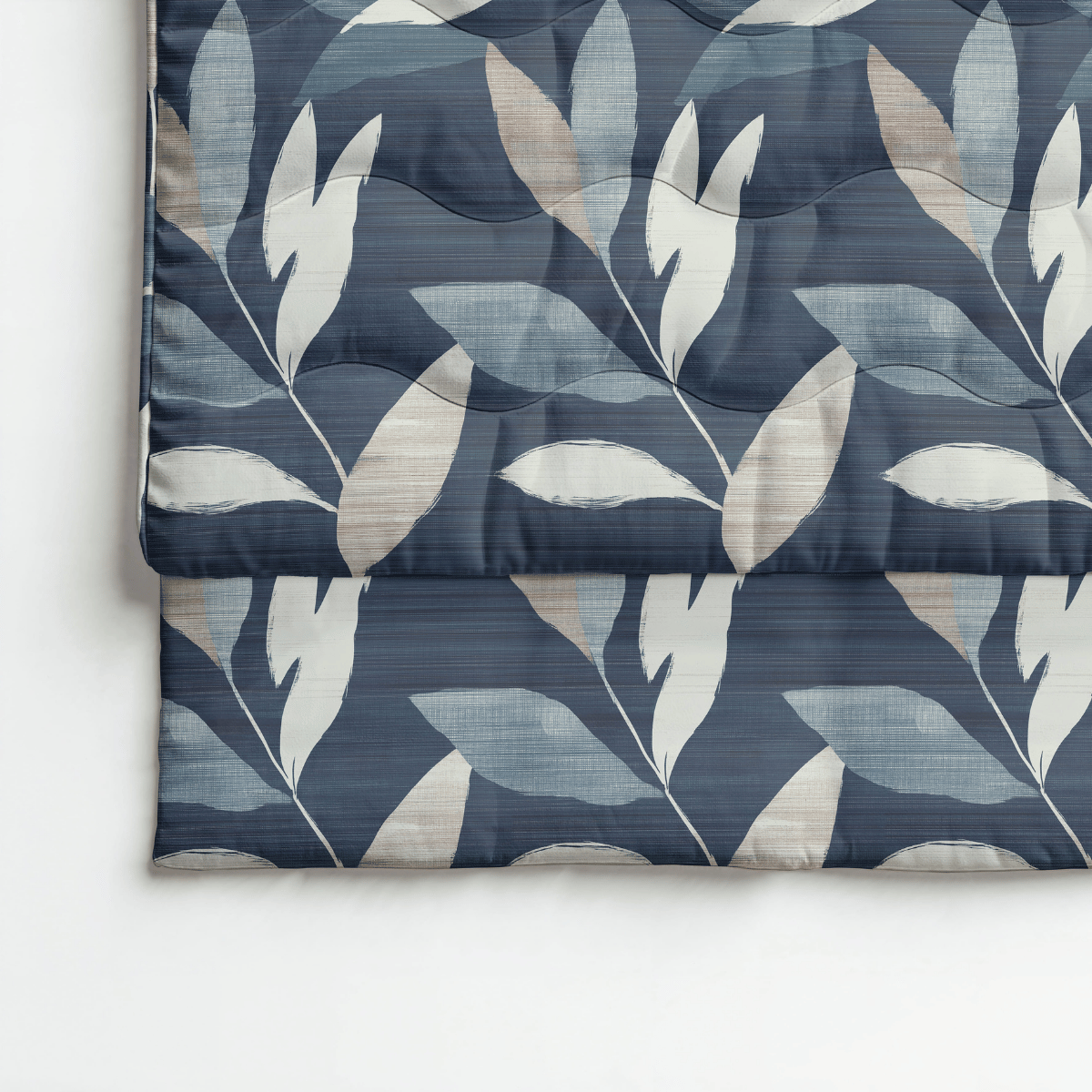 Die Royalbed Baumwolle - Dark Leaves Bettdecke verfügt über ein gefaltetes Design mit blauem Hintergrund, großen weißen und beigen Blattmustern und ist allergikergeeignet für maximalen Komfort.