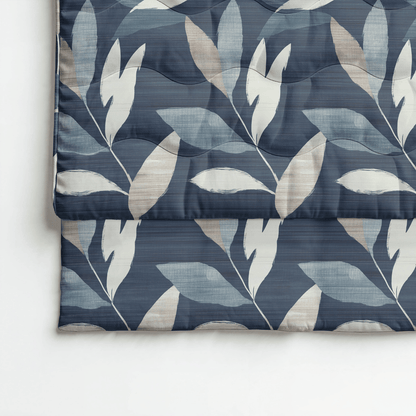 Die Royalbed Baumwolle - Dark Leaves Bettdecke verfügt über ein gefaltetes Design mit blauem Hintergrund, großen weißen und beigen Blattmustern und ist allergikergeeignet für maximalen Komfort.
