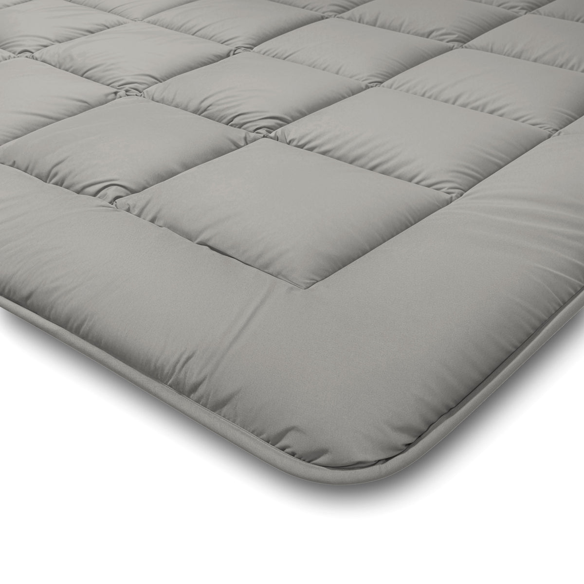 Nahaufnahme einer grauen Zelesta Comfort Duo Bettdecke - Grau & Sanftes Grau Matratzenauflage mit quadratischen Steppnähten und gepolsterten Abschnitten, die in einem Winkel vor einem weißen Hintergrund dargestellt ist.