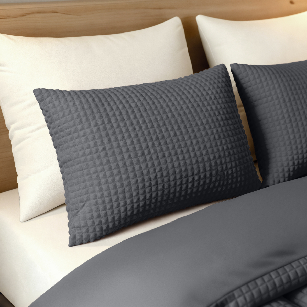 Ein ordentlich gemachtes Bett mit zwei weißen Kissen und zwei Zelesta Teddy Check Kissenbezügen - Anthrazit (80x80), passend zu einer dunkelgrauen superweichen Mikrofaser-Decke, alles waschmaschinengeeignet, vor einem hölzernen Kopfteil.