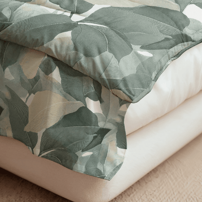 Die Royalbed Baumwolle - Green Forest Bettdecke mit grünem und beigem Blattmuster auf weißem Laken auf einem leichten Bettrahmen bietet allergikerfreundliche Bettwaren für einen erholsamen Schlaf.