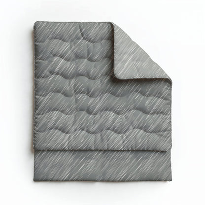 Eine gefaltete graue Steppdecke mit einem wellenförmigen Steppmuster und diagonalen weißen Linien, dargestellt auf Weiß. Die Royalbed Baumwolle - Mellow Stone ist temperaturregulierend und allergikerfreundlich für ultimativen Komfort.