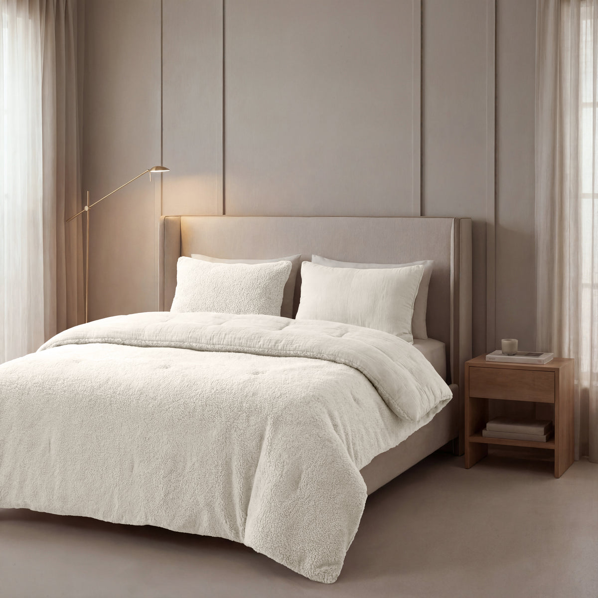 Ein ordentlich gemachtes Bett mit einem beige gepolsterten Kopfteil, Zelesta Teddy Baumwolle Musselin - Beige Bettwäsche und zwei Kissen neben einem hölzernen Nachttisch in einem sanft beleuchteten, neutral getönten Schlafzimmer.