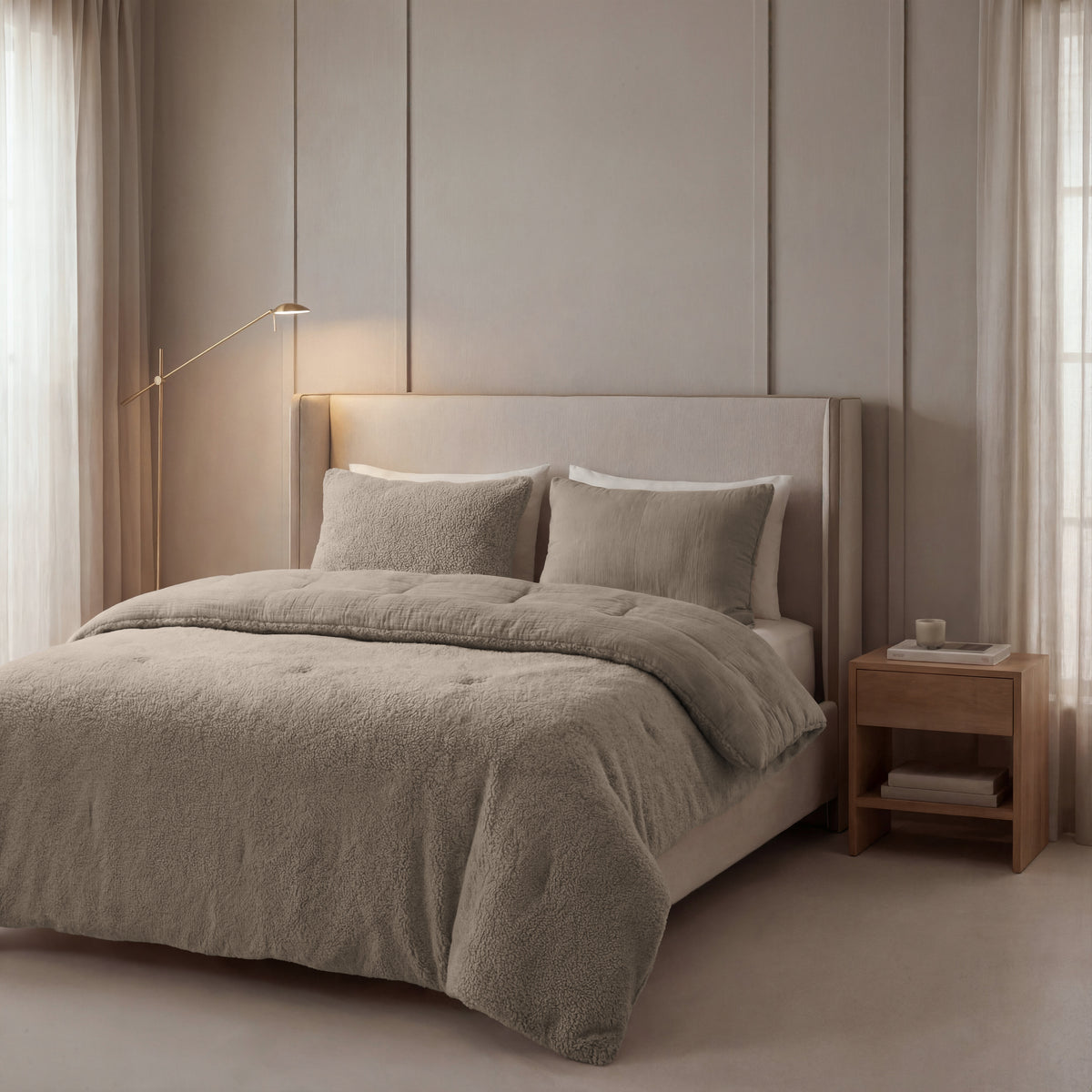 Ein modernes Schlafzimmer mit einem beigen Polsterbett, einer Zelesta Teddy Baumwolle Musselin - Taupe Bettdecke, passender Bettwäsche, einem Nachttisch aus Holz, einer minimalistischen Stehlampe und hellen Vorhängen.