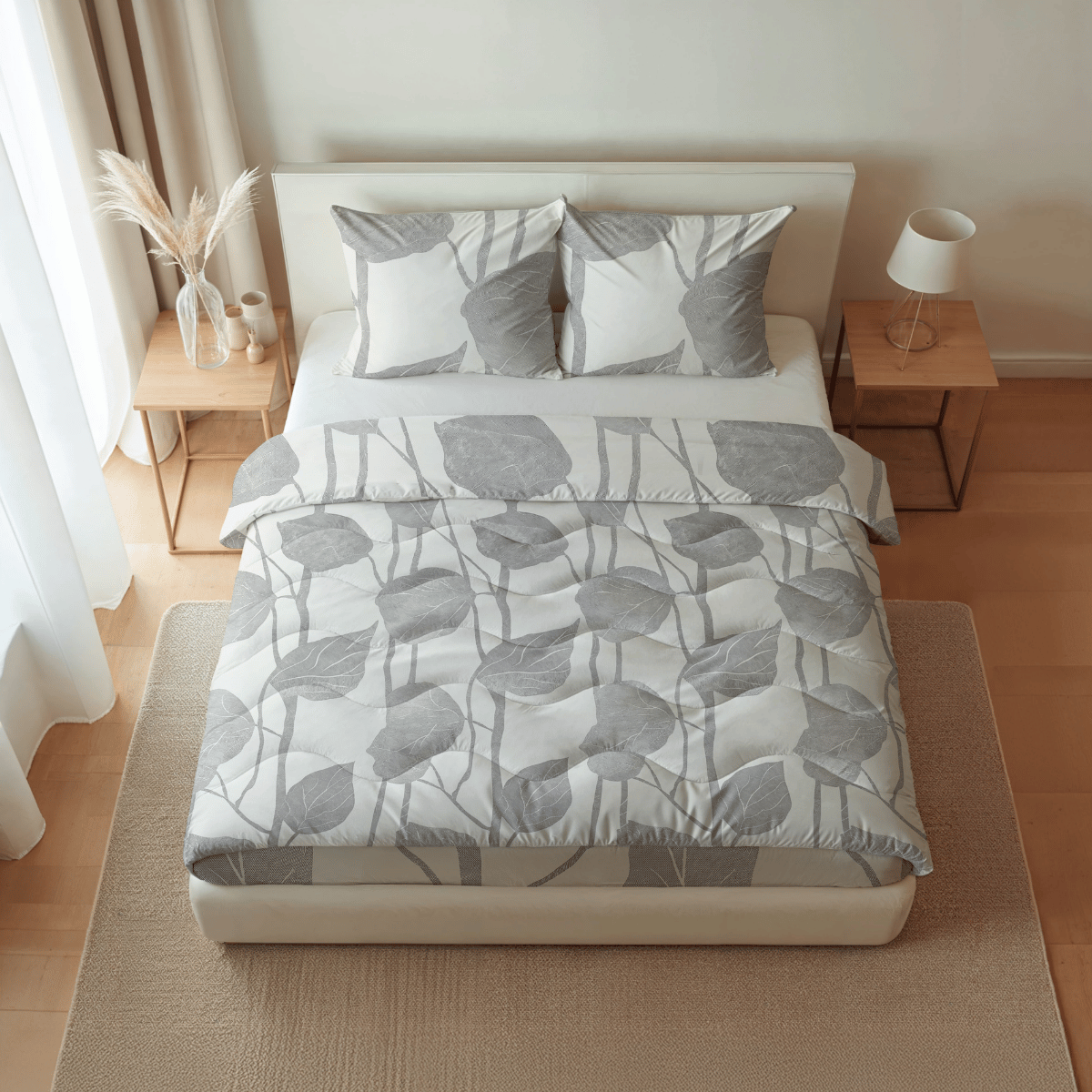 Ein ordentlich gemachtes Bett mit grauer, blattgemusterter Bettwäsche, passenden Kissen und hölzernen Nachttischen ist mit der Royalbed Baumwolle - Spring Buds temperaturregulierenden Bettdecke ausgestattet, die den Komfort in dem sanft beleuchteten Schlafzimmer erhöht.