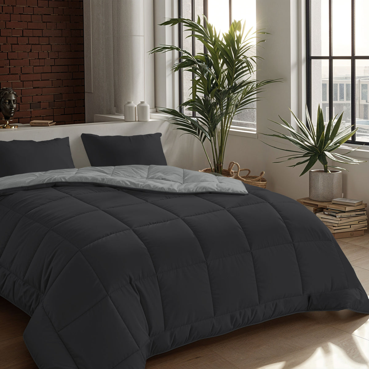 Ein modernes Schlafzimmer mit einer schwarzen Bettdecke und dem Zelesta Comfort Duo Kissenbezüge Set von 2 (80x80cm, sanftes Schwarz) aus weicher Mikrofaser, mit Topfpflanzen, Bücherstapeln und großen Fenstern, die den Raum mit Licht füllen.