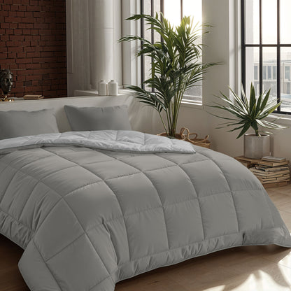 Ein ordentlich gemachtes Bett mit einer hellgrauen Mikrofaser-Bettdecke und zwei 80x80cm Zelesta Comfort Duo Kissenbezügen in Grau, neben großen Fenstern, Topfpflanzen und gestapelten Büchern auf dem Holzboden.