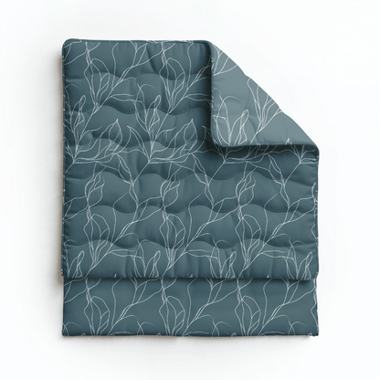 Die Royalbed Baumwolle - White Leaves Bettdecke ist in dunklem Teal mit einem weißen, abstrakten Blattmuster gefaltet - eine allergikerfreundliche Bettdecke perfekt für stilvollen, gemütlichen Komfort.