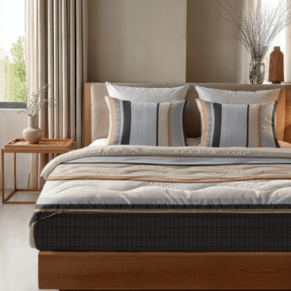 Ein ordentlich gemachtes Zelesta Royalbed - Blue Stripes mit passenden gestreiften Kissen steht neben einem hölzernen Beistelltisch mit einer Vase in einem sanft beleuchteten modernen Schlafzimmer.