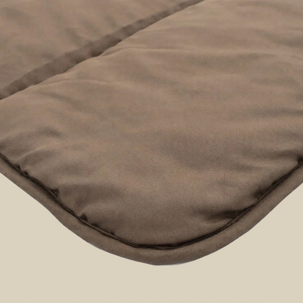 Nahaufnahme der Zelesta Comfort Uni Bettdecke - Mokka, mit einer braunen gepolsterten Stoffoberfläche mit sichtbaren Nähten und abgerundeten Kanten.