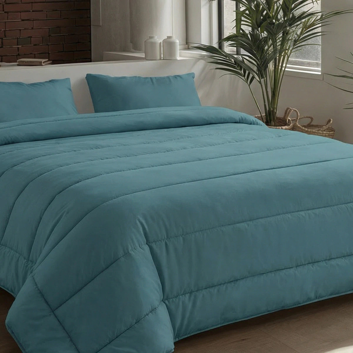 Ein ordentlich gemachtes Bett mit einer tealfarbenen Bettdecke und Zelesta Comfort Uni Kissenbezüge Set von 2 in Seegrün (80x80cm), aufgestellt in der Nähe eines Fensters mit einer Topfpflanze und dekorativen Gläsern auf der Fensterbank.