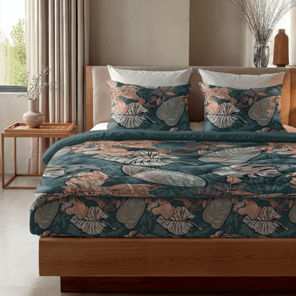 Das Zelesta Royalbed - Flower Power verfügt über eine tropische, blattgemusterte Bettwäsche in Teal, Pink und Beige mit einer wärmeregulierenden Bettdecke, ergänzt durch einen hölzernen Nachttisch und eine Vase mit getrockneten Zweigen.