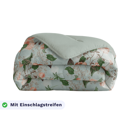 Eine gefaltete Zelesta Royalbed - Happy Flower Bettdecke mit floralem Muster und hellgrüner Rückseite. Ein Etikett unten links zeigt "Mit Einschlagstreifen" neben einem Häkchen.