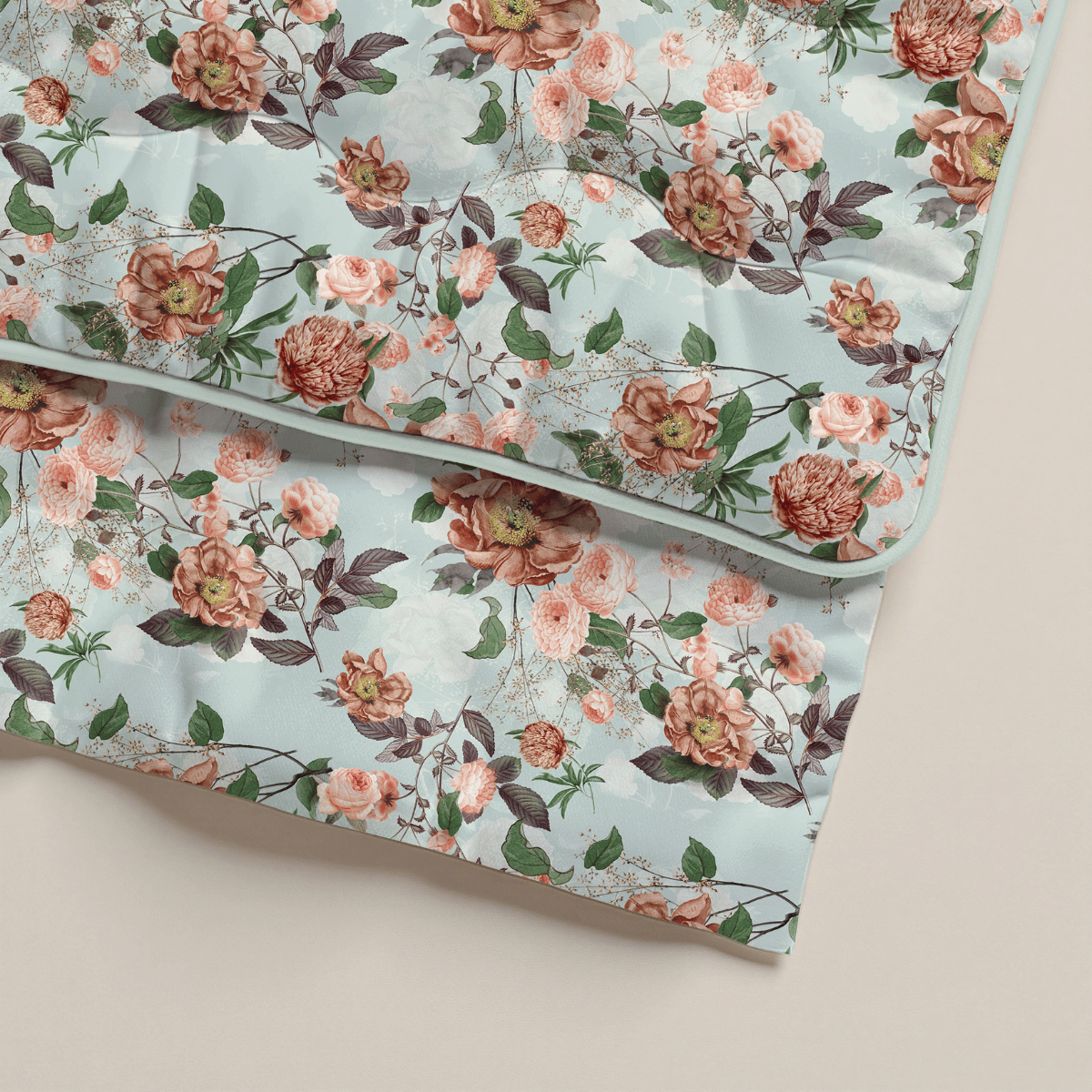 Zwei gefaltete Zelesta Royalbed - Happy Flower Bettdecken in hellblau mit rosa und roten Rosen, grünen Blättern und kleinen Zweigen. Gefertigt aus Mikrofaser Bettdecke, perfekt als antiallergische Bettdecke auf einem neutralen Hintergrund.