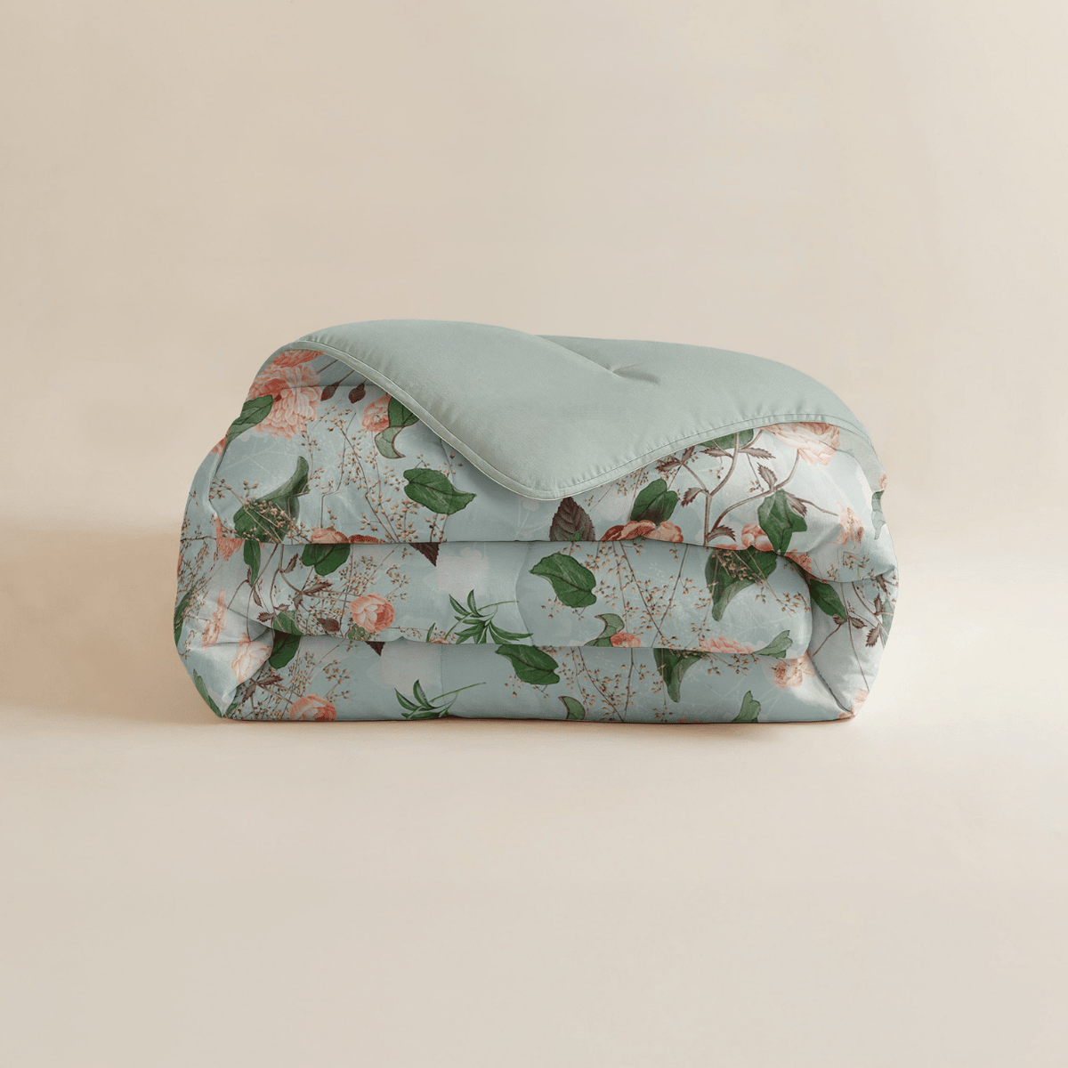 Eine sauber gefaltete Zelesta Royalbed - Happy Flower Mikrofaser Bettdecke mit einem hellblauen Oberteil und einem floralen Muster aus grünen Blättern und rosa Blüten.