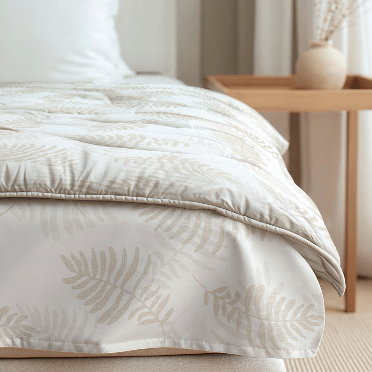 Nahaufnahme eines ordentlich gemachten Bettes mit dem Zelesta Royalbed - Oak Leafs, einer weißen Mikrofaser-Bettdecke mit beigem Eichenblattmuster, neben einem hölzernen Nachttisch mit einer beigen Vase und Trockenblumen.