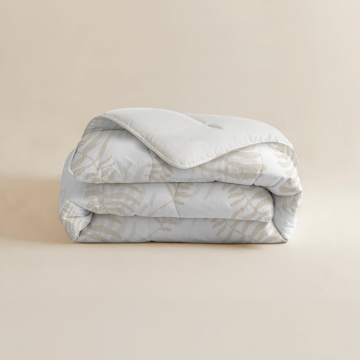 Eine fein säuberlich gefaltete Zelesta Royalbed - Oak Leafs Mikrofaser Bettdecke, die ein subtiles Eichenblattmuster in Beige auf hellem Hintergrund zeigt, das auf einer einfarbig beigen Oberfläche präsentiert wird.