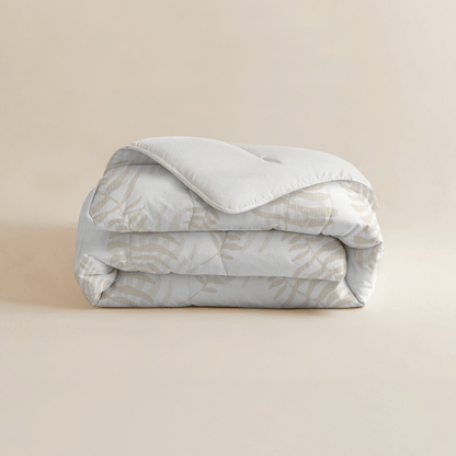 Eine fein säuberlich gefaltete Zelesta Royalbed - Oak Leafs Mikrofaser Bettdecke, die ein subtiles Eichenblattmuster in Beige auf hellem Hintergrund zeigt, das auf einer einfarbig beigen Oberfläche präsentiert wird.