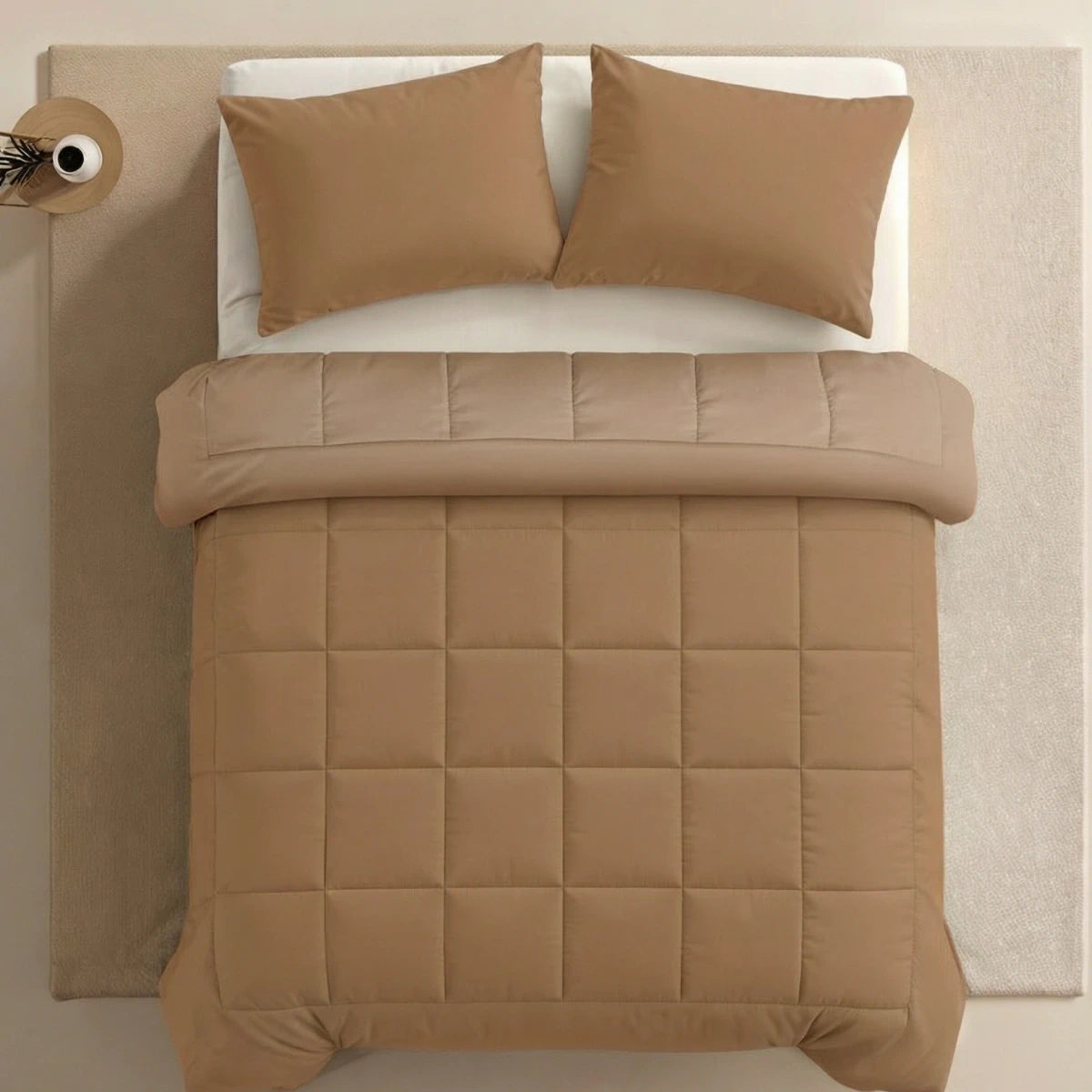 Ein ordentlich gemachtes Bett mit einer Zelesta Pure Uni Bettdecke in Kakao Braun und zwei passenden Kissen, von oben gesehen, auf einem hellen Teppich mit einem kleinen runden Beistelltisch.