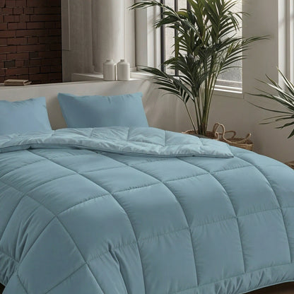 Ein ordentlich gemachtes Bett mit der Zelesta Pure Uni Bettdecke in Sereneblau und Kissen, in einem hellen Raum mit großen Fenstern, Grünpflanzen und dekorativen Gläsern auf der Fensterbank für atmungsaktiven Schlafkomfort.