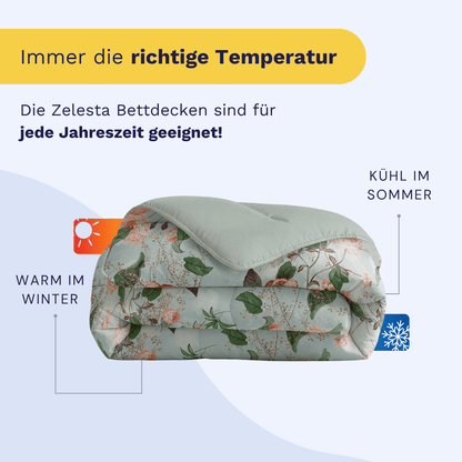 Abgebildet ist eine gefaltete Zelesta Royalbed - Happy Flower Bettdecke mit einem Text, der ihre Ganzjahrestauglichkeit hervorhebt - sie hält Sie im Winter warm und im Sommer kühl.