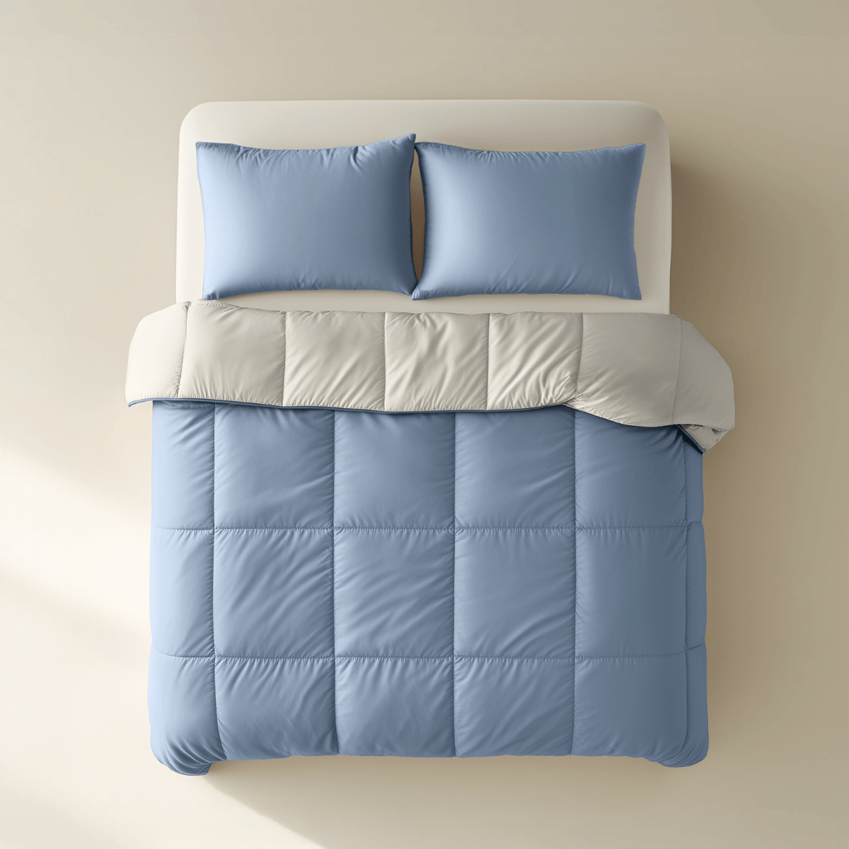 Ein gemachtes Bett mit zwei hellblauen Kissen, einem weißen Oberlaken und dem Zelesta Premiumbed Baumwolle - Dream Blue & Cream bietet ein luxuriöses Schlaferlebnis vor einem beigen Hintergrund.