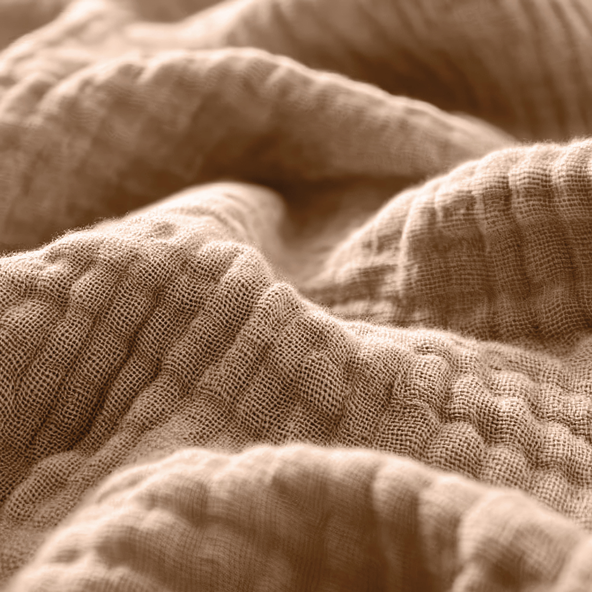 Nahaufnahme des Musselin Spannbettlaken - Terra in Beige mit seiner strukturierten, wellenförmig gesteppten Oberfläche und dem sichtbaren Bindungsmuster.