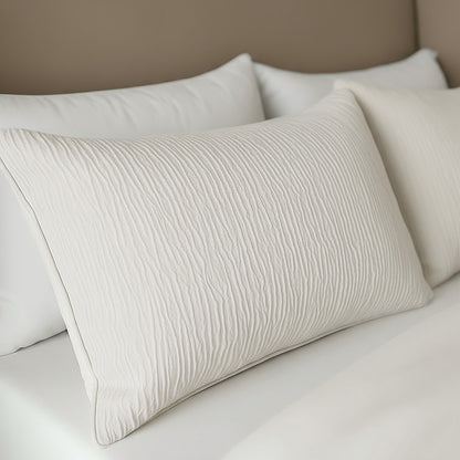 Eine Nahaufnahme eines ordentlich gemachten Bettes mit dem Zelesta Velvetbed Chique Kissenbezüge Set von 2 in Beige und knackig weißer Bettwäsche vor einem beigen Kopfteil, das einen eleganten Touch verleiht.