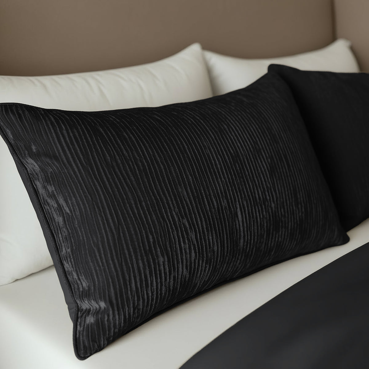Zwei Zelesta Velvetbed Chique Kissenbezüge Set von 2 - Black werden nebeneinander auf dem Bett mit weißen Laken und einer schwarzen Decke platziert, wodurch ein pflegeleichter und stilvoller Look entsteht.