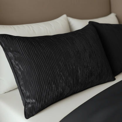 Zwei Zelesta Velvetbed Chique Kissenbezüge Set von 2 - Black werden nebeneinander auf dem Bett mit weißen Laken und einer schwarzen Decke platziert, wodurch ein pflegeleichter und stilvoller Look entsteht.